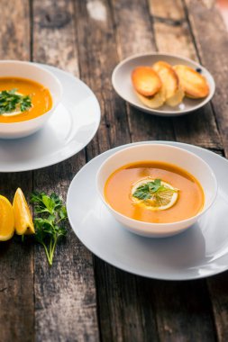 Bir dilim limon ve beyaz bir tabak içinde maydanoz ile mercimek kabak çorbası