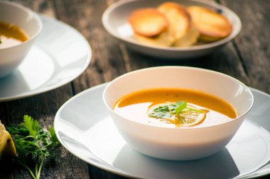 Bir dilim limon ve beyaz bir tabak içinde maydanoz ile mercimek kabak çorbası