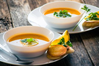 Bir dilim limon ve beyaz bir tabak içinde maydanoz ile mercimek kabak çorbası