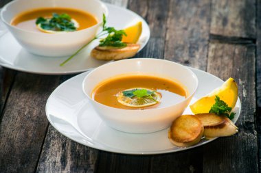 Bir dilim limon ve beyaz bir tabak içinde maydanoz ile mercimek kabak çorbası