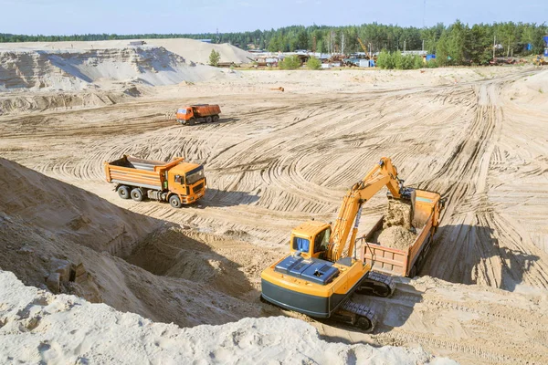 Work of the excavator and truck at a sand quarry. Excavator loading sand into a dump truck.