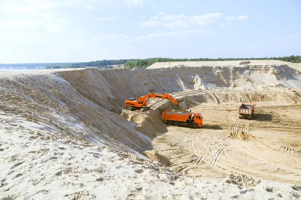 Work of the excavator and truck at a sand quarry. Excavator loading sand into a dump truck.