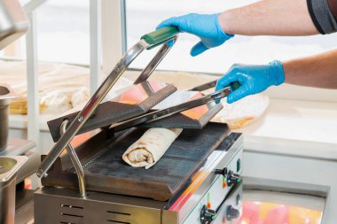 Cook bir elektrikli ocakta shawarma hazırlar