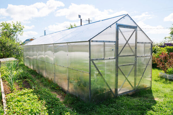 Polycarbonate greenhouse in the garden. Triangular roof.