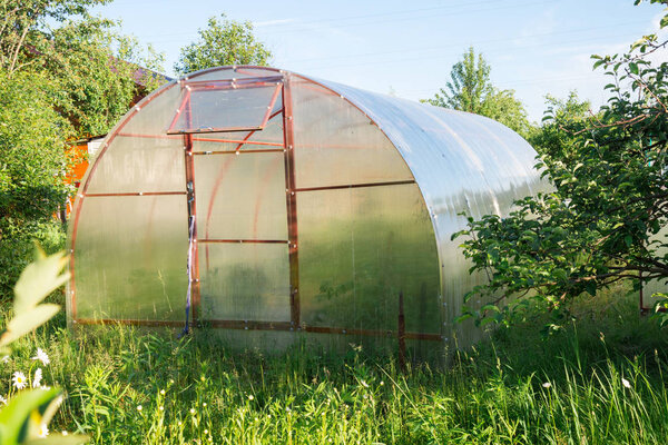 Polycarbonate greenhouse in the garden. Semicircular shape