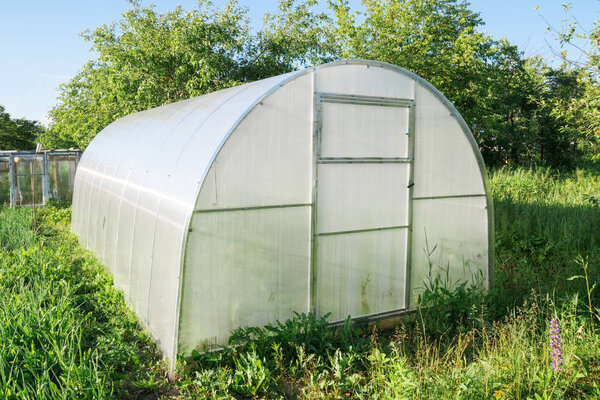 Polycarbonate greenhouse in the garden. Semicircular shape