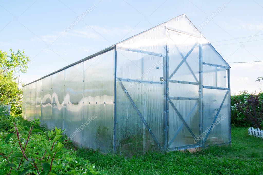 Polycarbonate greenhouse in the garden. Triangular roof.