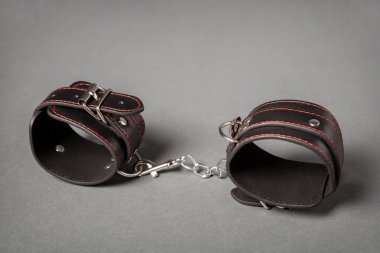 Siyah deri gri arka plan üzerinde kelepçe. Seks oyuncak.