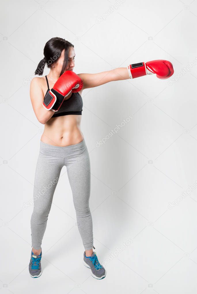 Sporty sexy girl in Boxing gloves on a white background. Direct hit.