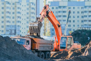 Ekskavatör toprak bir damperli kamyon yükler. İnşaat sitesinde çalışmak.