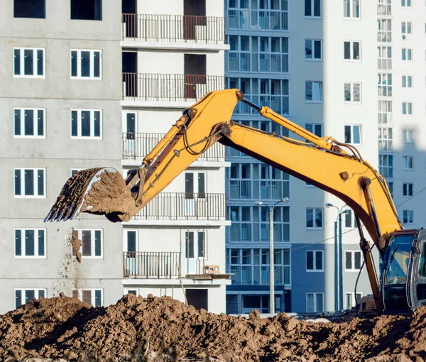 Yellow excavator digging the ground at the construction site.