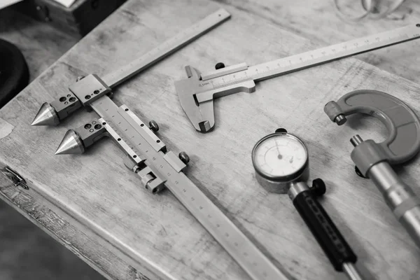 Metal measuring instruments on a wooden table. Product quality control. Black and white.