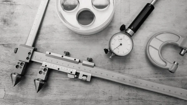 Metal measuring instruments on a wooden table. Product quality control. Black and white.