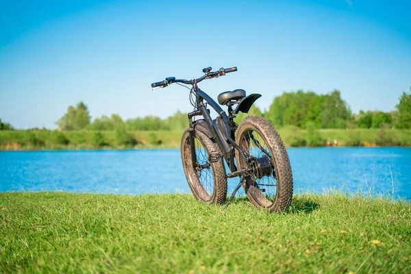 湖边有大轮子的电动自行车 一个愉快的运动爱好 让你可以旅行 胖子车 免版税图库图片