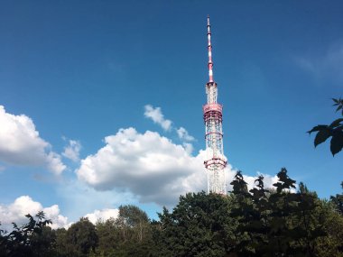 Parkın yanındaki yüksek televizyon kulesi. Güzel doğası, yeşil çalılar, halka açık park ve mavi gökyüzü ile Telekomünikasyon Kulesi. Büyük bulutlar ile güzel gökyüzü