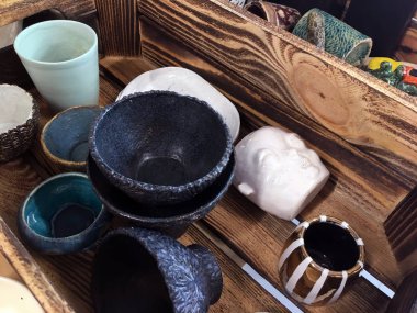 Seramik tabaklar ve tabaklar ahşap bir kutuda. Dekoratif seramik kafa. Masa takımı ve dekor. Derin seramik kaseler. Boş siyah seramik servis kasesi. Dekoratif yemekler.