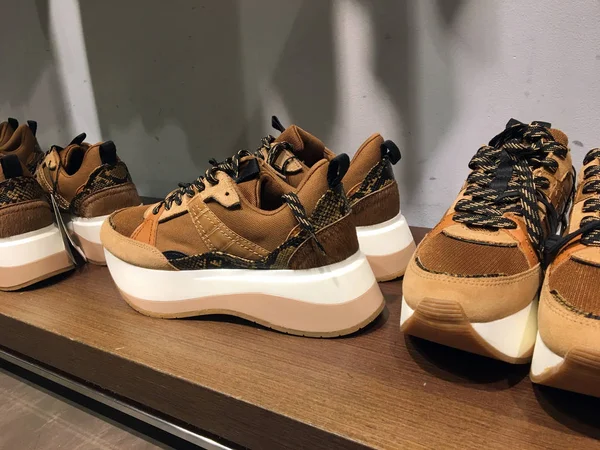 Ayakkabı mağazasında rafta yılan baskılı kahverengi platform spor ayakkabılar. Toplu pazar dükkanı. Moda Casual Kadın Sneakers Yakın Görünümü. Kadınlar için Yüksek Platform Lu Spor Ayakkabılar. Moda Casual spor ayakkabıları Yakın Görünümü