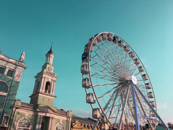 Big Ferris Wheel in the city in the evening. Big atraktsion ferris wheel on the background of a beautiful blue sky with clouds. Attraction wheel review over park at summer evening time