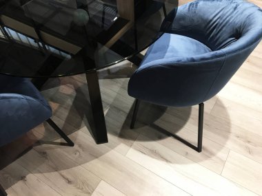 Masalı sandalyeler. Odada kumaş sandalye ile yemek cam masa. Üst te. Mavi yumuşak sandalyeler. Modern ve rahat iç mekan.