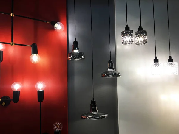 Display of many hanging lamps with colorful lamp shade sizes and colors in dark room. A group of hanging lights with shallow depth of field. Installation. Many lampshades