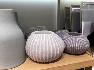 Bir mağazada bir rafta çeşitli şekillerde vazolar. Gri minimalist uzun vazo. Dalgalı seramik vazolar. Dekor ve sofra dükkanı. Raflarda belirlenen renkli vazolar çeşitli