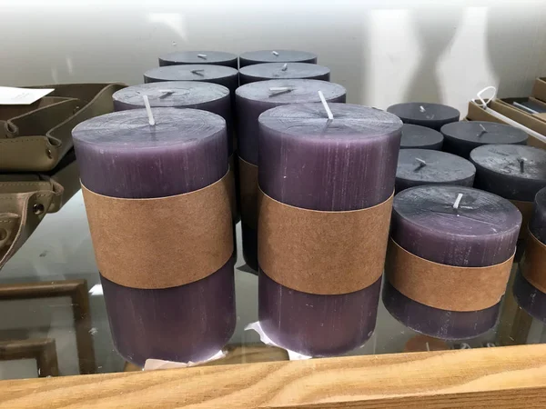 Bir dekor mağazasında cam bir rafta mor tasarımcı mumlar. Mağazalarda çeşitli boyutlarda, şekil ve renk mumlar. Farklı boyutta mumlar. Pastel aroma mumlar