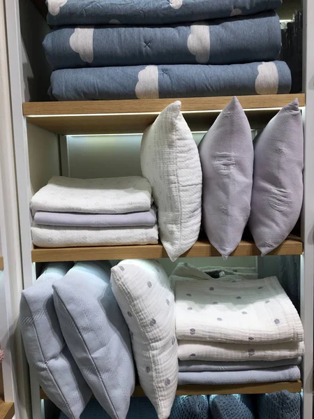 Battaniye ve yastık yığını rafta. Gardıroptaki raflarda katlanmış kışlık giysiler. Yatak, masa ve banyo malzemeleri satan mağazalarda satılık havlular. Ticari mallar mağazanın içinde düzenlenir