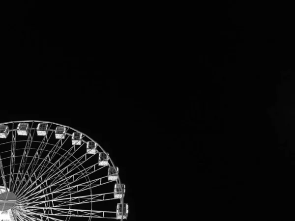 Ferris wheel in blue neon light on dark background, Part of Ferris wheel with blue illumination against a black sky background at night. Park at night, beautiful city