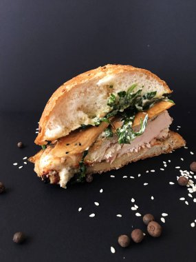 Siyah arka planda kızarmış tavuk burger. Hamburgerin beyaz kağıdıyla yakın plan görüntüsü. Geleneksel fast food. Tasarım için alanı kopyala. Sağlıksız yiyecekler. Lezzetli ızgara ve tavuk burger. Baharatlar 