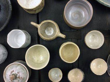 Karanlık ahşap üzerine modern çömlek. Dekoratif seramik tabak. El yapımı koyu çömlek. Seramik kil boş el yapımı kaseler ve koyu arkaplanda bardak. Çömlek, toprak, mutfak gereçleri..