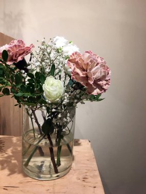 Küçük cam vazo, bir buket gül ve ahşap kutuda kurutulmuş çiçekler. Düğün dekoru. Gül ve yeşil dallı küçük cam vazo. İçi çiçeklerle dolu.