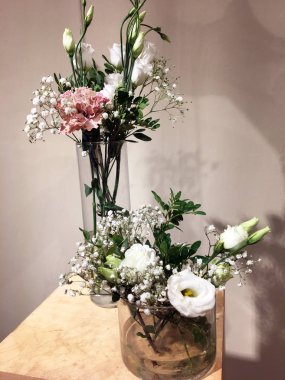 Küçük cam vazo, bir buket gül ve ahşap kutuda kurutulmuş çiçekler. Düğün dekoru. Gül ve yeşil dallı küçük cam vazo. İçi çiçeklerle dolu.