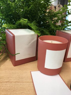 Ahşap raftaki kırmızı seramik kavanozda kokulu mum. Kozmetik ve dekor dükkanında eğreltiotu kursu. Kokulu mumlar mağazada satılır. Aromaterapi konsepti. Spa
