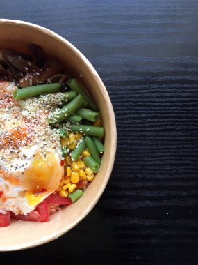 Koyu ahşap masada kağıt ambalajda yumurta ve sebzeli sağlıklı dürtme kabı. Tavuk, mantar, kuşkonmaz, mısır, salatalık ve brokoli. Spor yemeği. Öğle yemeği vakti. Yiyecek konsepti