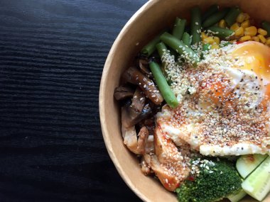 Koyu ahşap masada kağıt ambalajda yumurta ve sebzeli sağlıklı dürtme kabı. Tavuk, mantar, kuşkonmaz, mısır, salatalık ve brokoli. Spor yemeği. Öğle yemeği vakti. Yiyecek konsepti