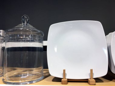 Mağazanın rafında beyaz seramik tabaklar. Desenci seramik plakalar. Masa düzenleme, sofra takımı ve yeme konsepti. Süpermarketin raflarında çeşitli şık yemek çeşitleri.