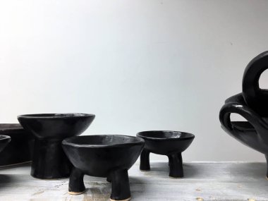 Ahşap rafta modern çömlek. Dekoratif seramik tabak. El yapımı koyu çömlek. Seramik kil boş el yapımı kase ve koyu arkaplanda bardak. Çömlek, toprak, mutfak gereçleri..