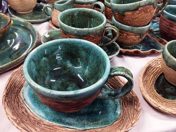 Green rustic clay jugs on white fabric. Terracotta ceramic dishes. Collection of dishes for the kitchen selling in the store. National pottery. Environmentally friendly ceramic dishes cups