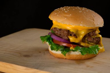 Tahta Masada Peynirli Lezzetli Izgara Hamburger. Karanlık Arkaplanda Marul Peynirli Soğanlı Lezzetli Hamburger. Metin için Boş Alan.