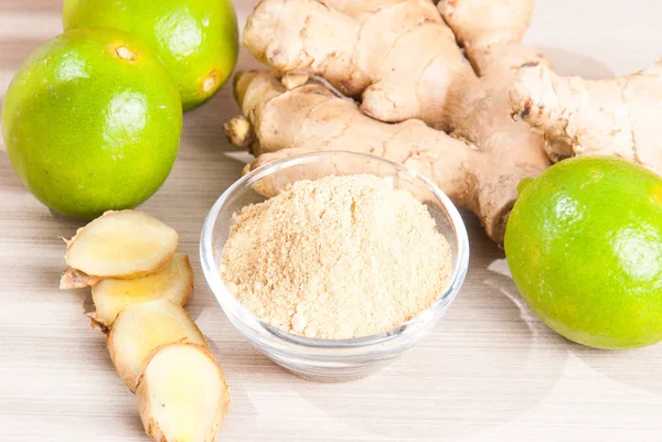 Ginger root and ginger powder on wooden background