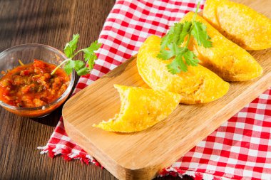 Empanada colombiana con salsa picante sobre fondo de madera