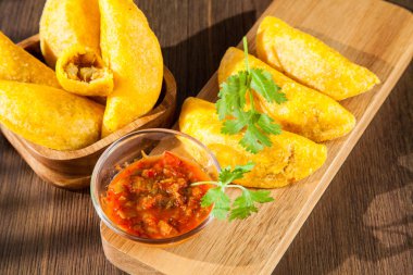 Empanada colombiana con salsa picante sobre fondo de madera