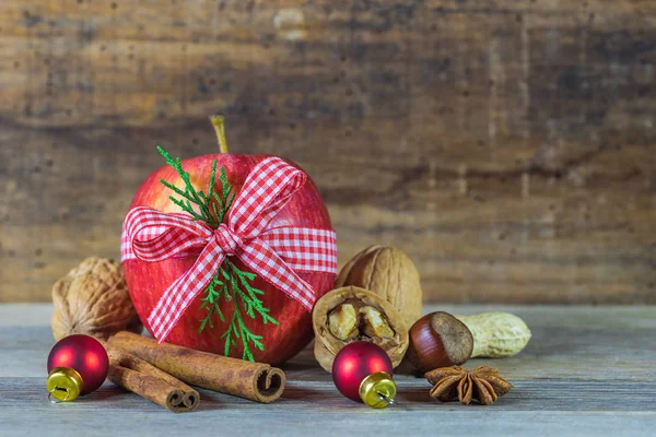 Christmas holiday season still life with food, red apple, nuts and spices and wood background
