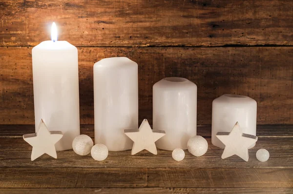 Traditional Advent candles with white star shapes and balls decoration on wooden table, first Advent