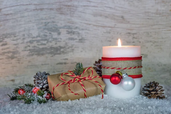 Christmas composition with burning candle and gift box on snow