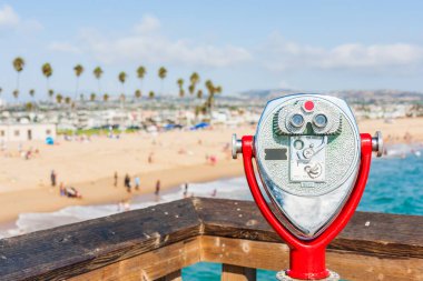 Newport Beach Pier, Güney Kaliforniya, ABD 'de madeni para ile çalışan teleskop.