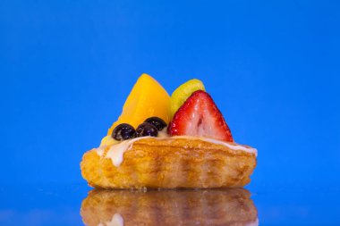 Mavi arkaplanda renkli meyveli tart