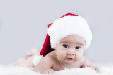 çok güzel parlak duygusal mutlu küçük bebek beyaz ekose üzerinde sürünerek Noel Baba şapkası