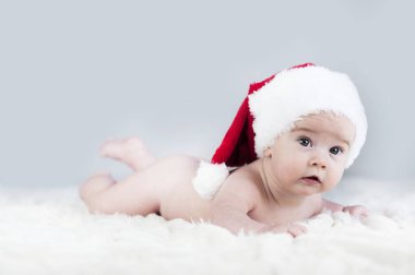 çok güzel parlak duygusal mutlu küçük bebek beyaz ekose üzerinde sürünerek Noel Baba şapkası