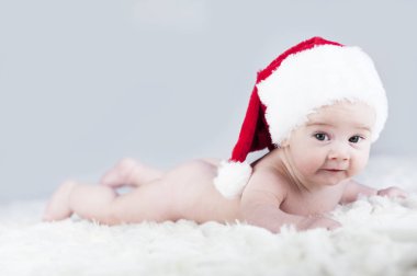 çok güzel parlak duygusal mutlu küçük bebek beyaz ekose üzerinde sürünerek Noel Baba şapkası